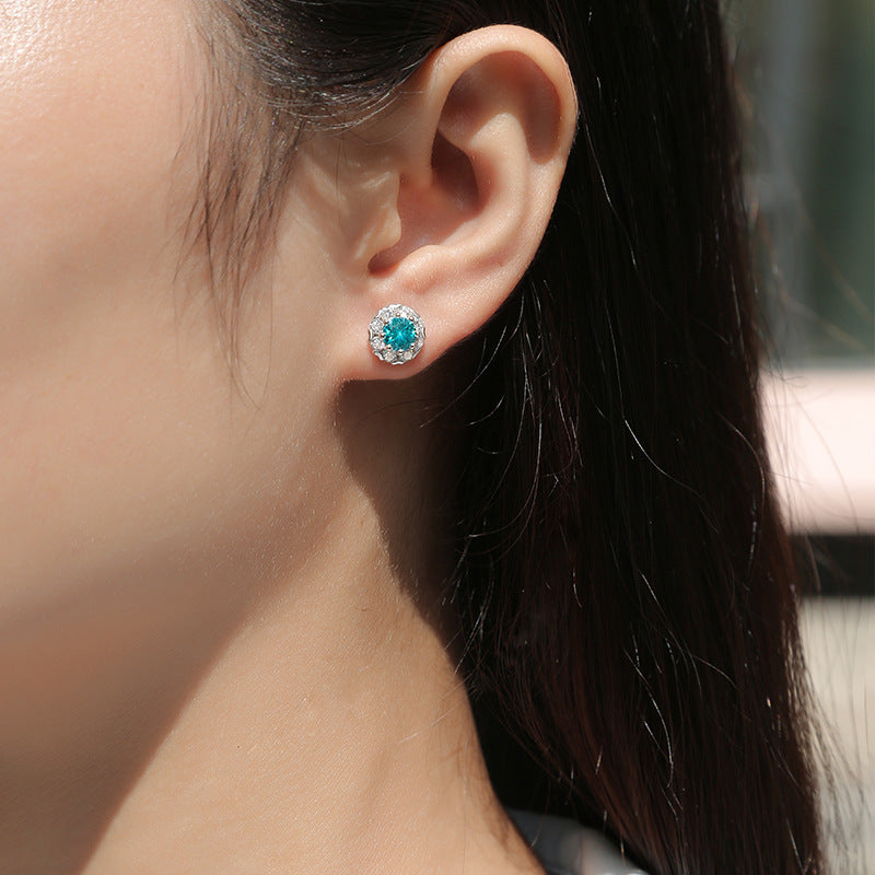 Image of woman wearing the 0.5ct Blue Round Cut Moissanite Earrings in 925 Sterling Silver on her left ear